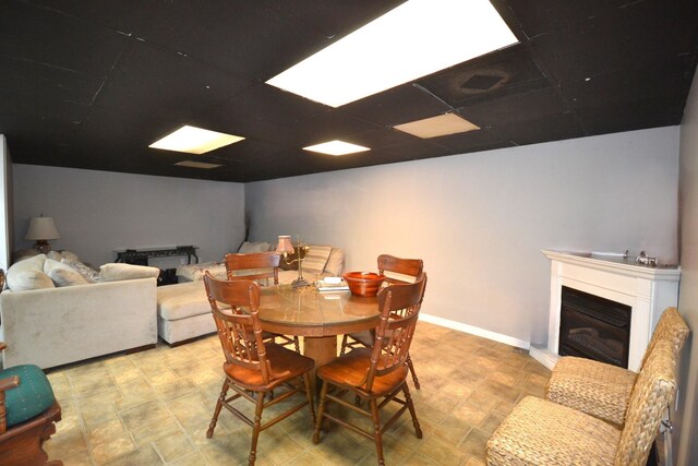 dining space featuring a drop ceiling, baseboards, and a fireplace