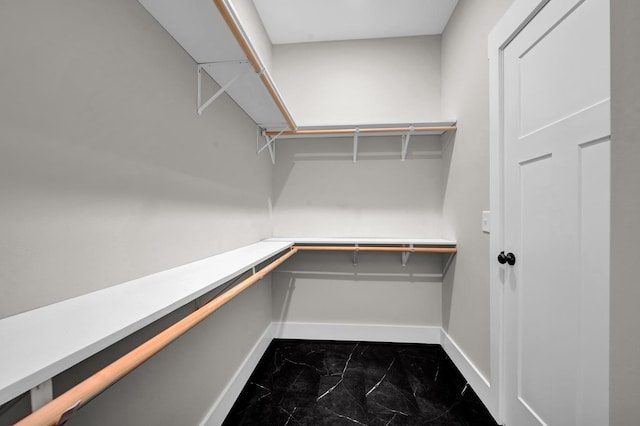  - walk in closet with dark marble finish flooring