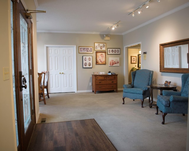 sitting room with carpet flooring, crown molding, and track lighting