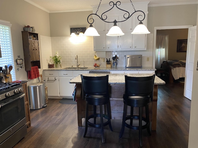 kitchen with white cabinetry, sink, tasteful backsplash, stainless steel range with gas cooktop, and decorative light fixtures