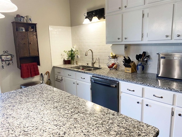 kitchen with white cabinets, backsplash, stainless steel dishwasher, and sink