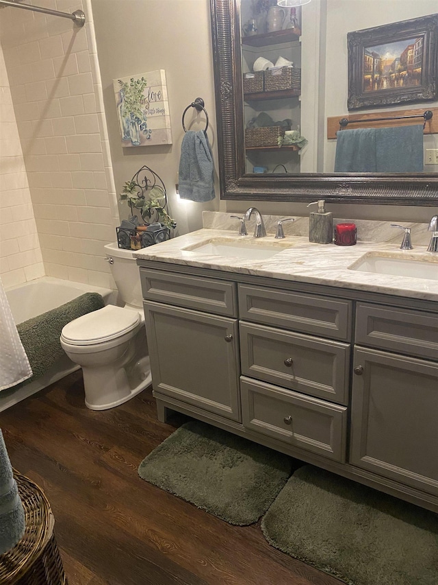 full bathroom with vanity, toilet, wood-type flooring, and shower / tub combo