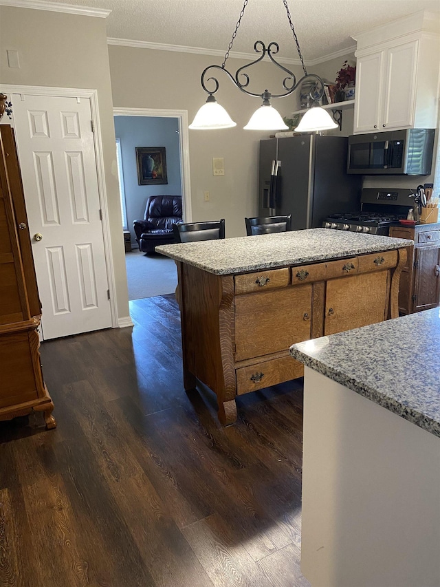 kitchen featuring stainless steel appliances, crown molding, decorative light fixtures, dark hardwood / wood-style floors, and white cabinetry