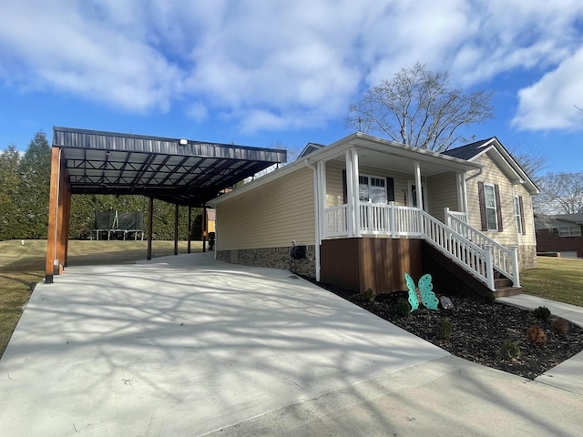 view of property exterior featuring a trampoline, covered porch, and a carport