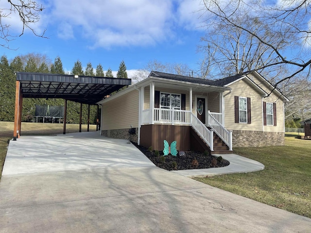 view of front of home featuring a carport, a front lawn, covered porch, and a trampoline