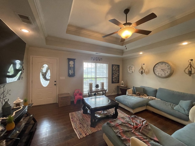 living room with a tray ceiling, ceiling fan, dark hardwood / wood-style floors, and ornamental molding