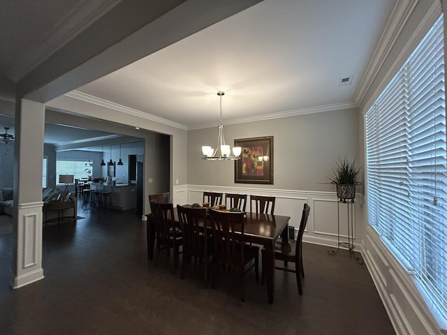 - dining area featuring a chandelier, a decorative wall, crown molding, and wainscoting