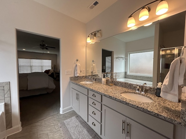  - ensuite bathroom with a ceiling fan, plenty of natural light, a bath, and double vanity