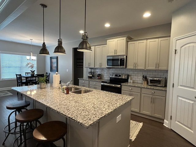  - kitchen with appliances with stainless steel finishes, a sink, dark wood-type flooring, decorative backsplash, and an island with sink