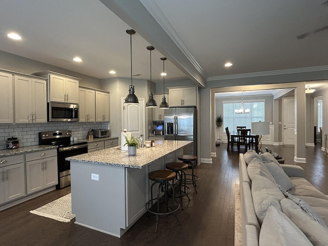  - kitchen with appliances with stainless steel finishes, ornamental molding, a chandelier, dark wood-style floors, and backsplash