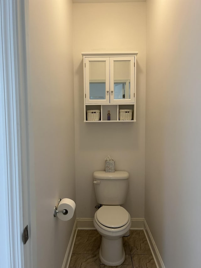  - bathroom with baseboards, toilet, and marble look tile flooring