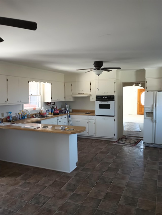 kitchen with under cabinet range hood, white appliances, a peninsula, white cabinets, and ceiling fan