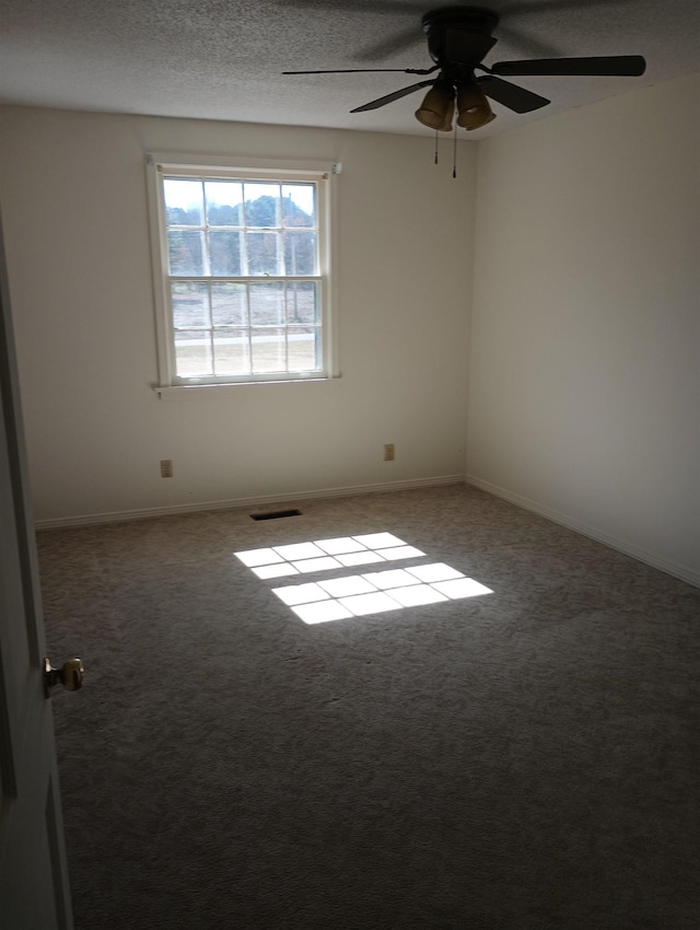 carpeted spare room featuring baseboards, visible vents, a textured ceiling, and a ceiling fan