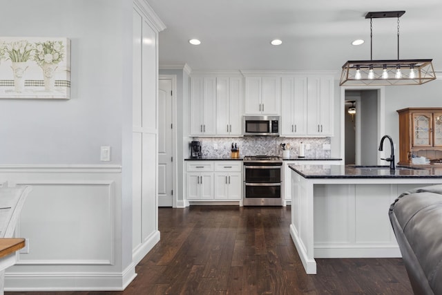 kitchen featuring backsplash, appliances with stainless steel finishes, a sink, and white cabinetry