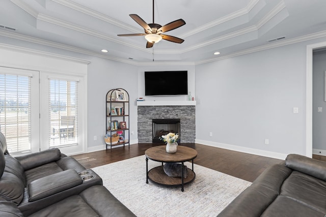living area with ceiling fan, dark wood-style flooring, a tray ceiling, and visible vents