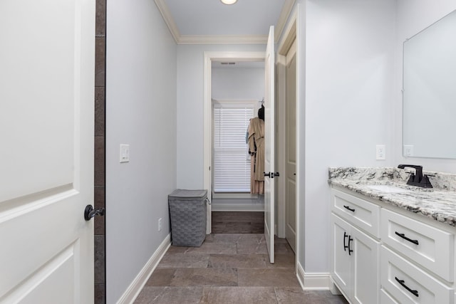 bathroom with baseboards, stone finish flooring, vanity, and crown molding