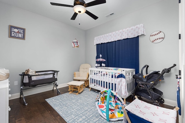 bedroom with baseboards, visible vents, wood finished floors, ceiling fan, and a nursery area