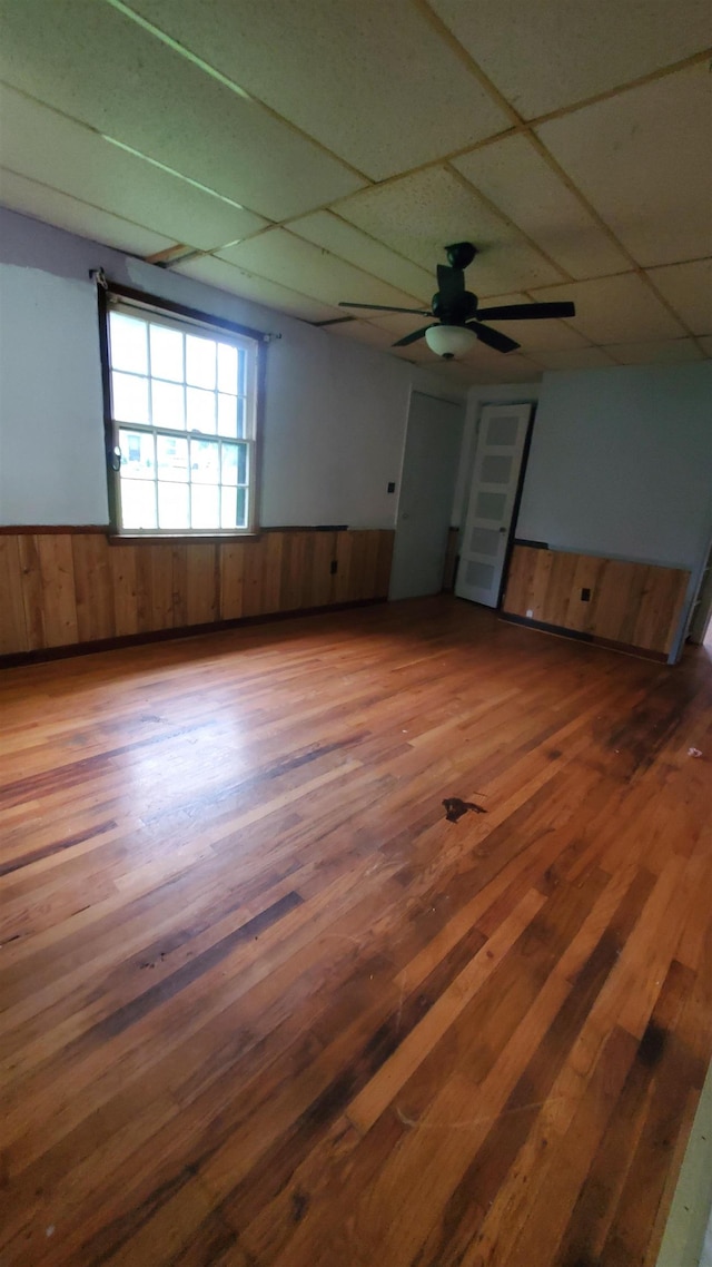 spare room with dark hardwood / wood-style flooring, a paneled ceiling, wooden walls, and ceiling fan