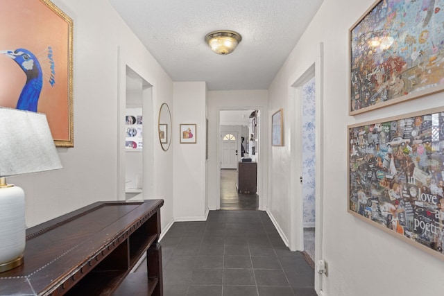 hall featuring a textured ceiling and dark tile patterned floors