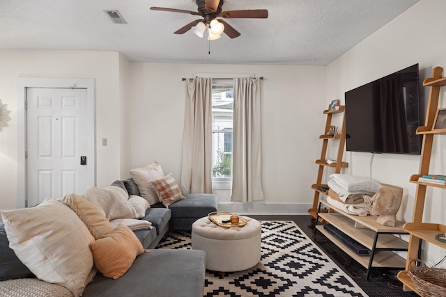 living room with ceiling fan, dark hardwood / wood-style flooring, and a textured ceiling