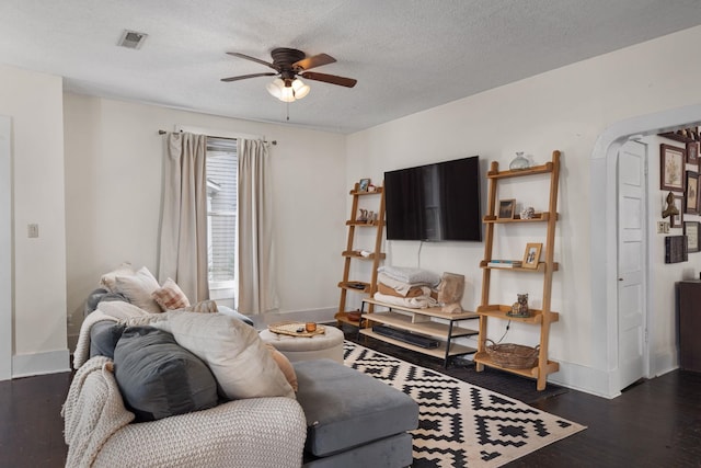 living room featuring ceiling fan, dark hardwood / wood-style floors, and a textured ceiling