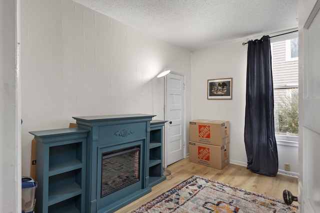 sitting room with light wood-type flooring and a textured ceiling