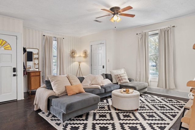 living room featuring ceiling fan, a textured ceiling, and dark hardwood / wood-style flooring