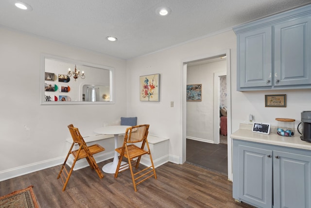 dining space featuring a textured ceiling, an inviting chandelier, ornamental molding, and dark hardwood / wood-style floors