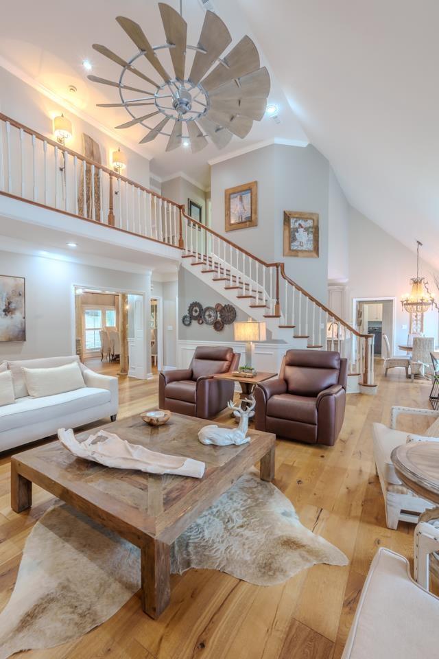  - living room featuring high vaulted ceiling, stairs, light wood-type flooring, ceiling fan, and ornamental molding