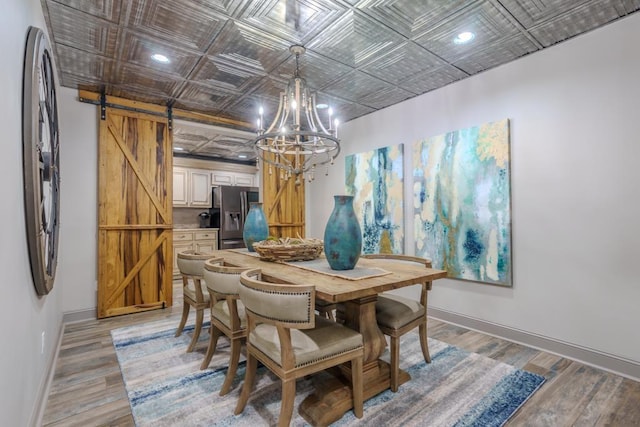  - dining area with a barn door, an ornate ceiling, baseboards, a chandelier, and light wood-type flooring
