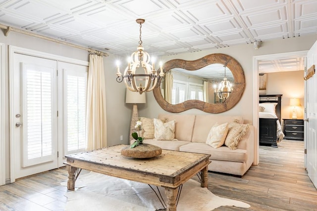  - living room featuring a chandelier, light wood-type flooring, plenty of natural light, and an ornate ceiling