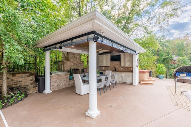  - view of patio with a gazebo, an outdoor stone fireplace, ceiling fan, fence, and a sink