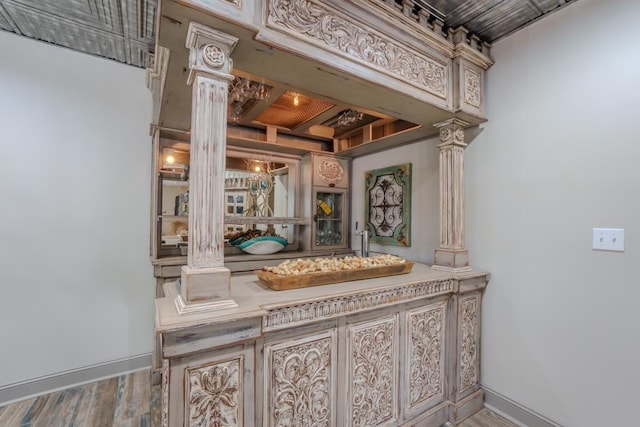  - bar area featuring decorative columns, wood finished floors, and baseboards