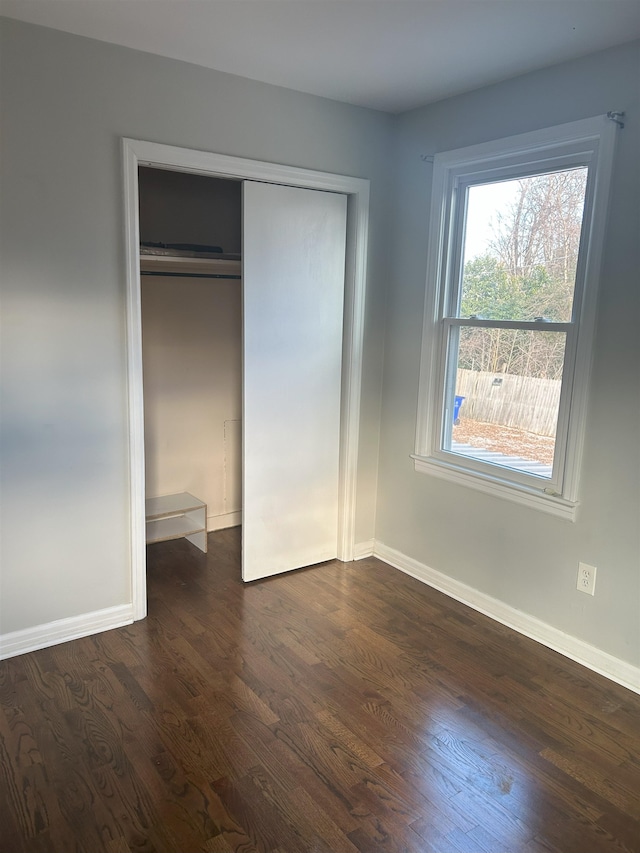 unfurnished bedroom with a closet and dark hardwood / wood-style floors