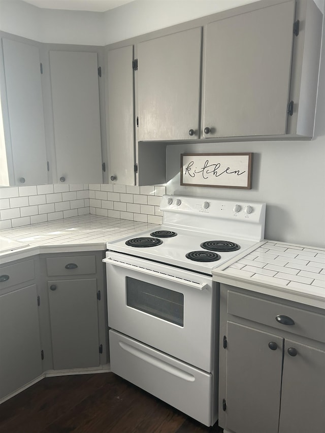 kitchen featuring gray cabinetry, dark wood-type flooring, and white electric range oven