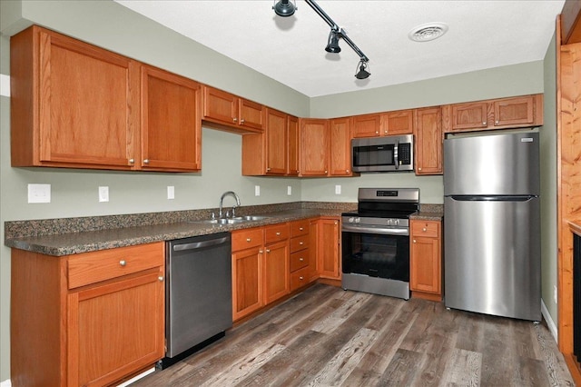 kitchen featuring track lighting, sink, appliances with stainless steel finishes, and dark wood-type flooring