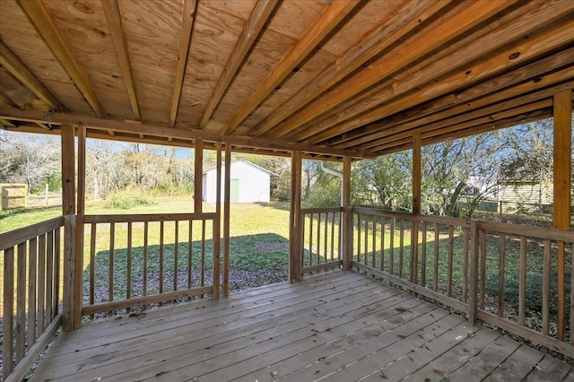 wooden deck with a lawn and a storage unit