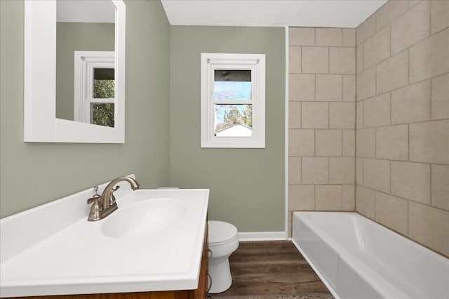 full bathroom featuring hardwood / wood-style floors, vanity, toilet, and tiled shower / bath combo