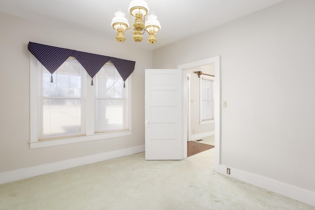 carpeted empty room with an inviting chandelier