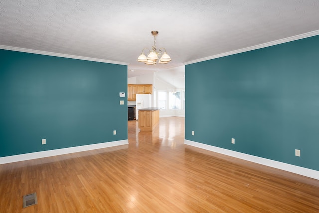 empty room with an inviting chandelier, ornamental molding, a textured ceiling, and light wood-type flooring