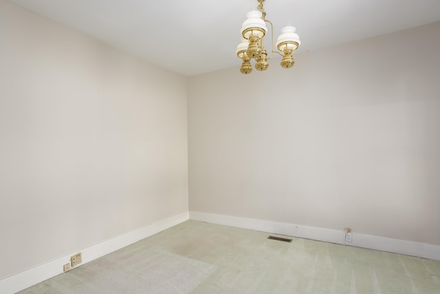 carpeted spare room featuring a chandelier