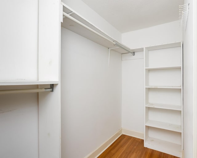 walk in closet with dark hardwood / wood-style floors