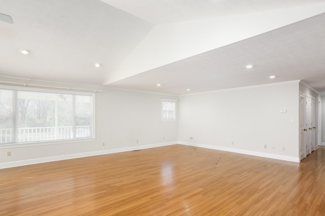 empty room with crown molding, vaulted ceiling, and light hardwood / wood-style floors