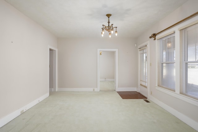 carpeted spare room featuring a chandelier