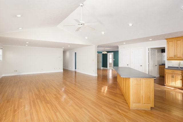 kitchen with lofted ceiling, ceiling fan with notable chandelier, light hardwood / wood-style floors, and a center island