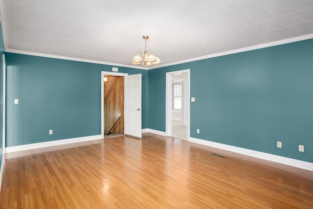 empty room with ornamental molding, wood-type flooring, and a chandelier