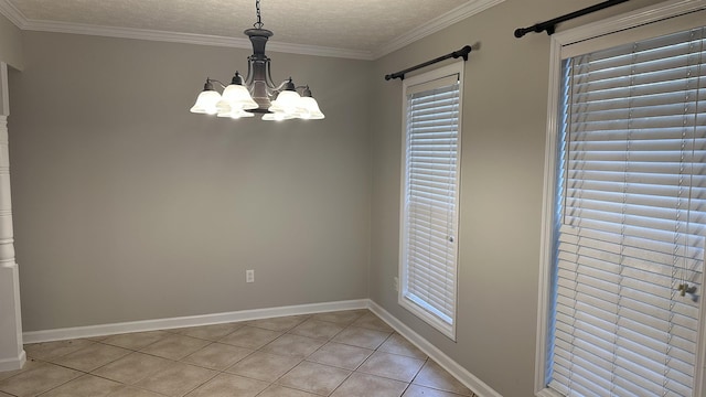 tiled empty room featuring a chandelier, a textured ceiling, and ornamental molding