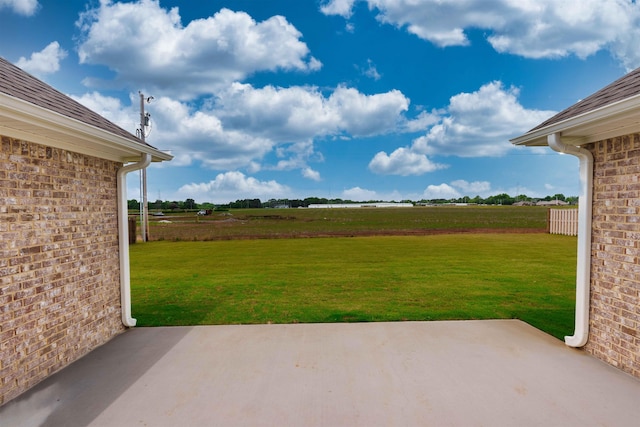  - view of green lawn with a patio area and a rural view
