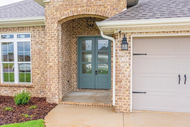  - doorway to property featuring roof with shingles, brick siding, french doors, and an attached garage