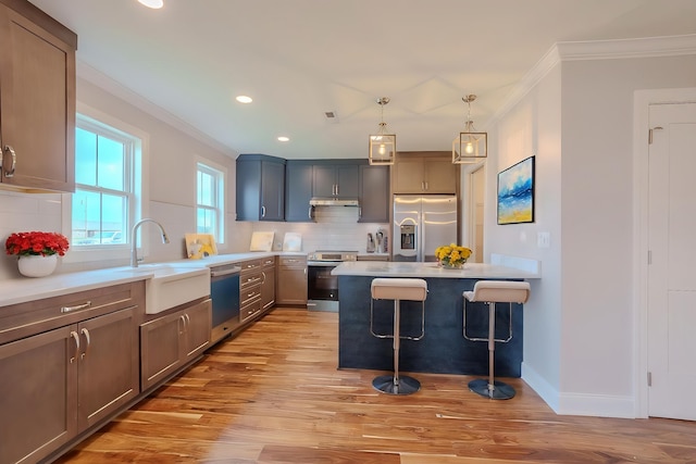  - kitchen with stainless steel appliances, crown molding, a kitchen bar, light wood-type flooring, and tasteful backsplash